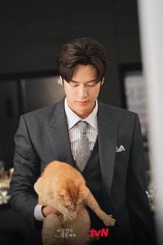 a man in a suit holding an orange cat