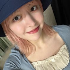 a woman with pink hair wearing a blue hat