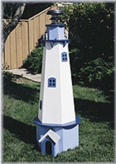 a blue and white lighthouse sitting in the grass