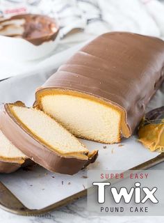 a loaf of cake sitting on top of a white plate next to a piece of chocolate