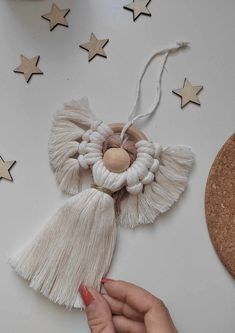 a hand holding a tasseled decoration on top of a white table next to stars