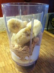 a blender filled with lots of different types of ingredients on top of a wooden table