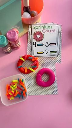 a pink table topped with plastic toys and doughnuts