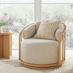 a living room with a round chair and side table in front of large windows that look out onto the outdoors