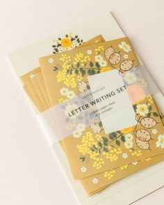 four letter writing sets with yellow flowers and teddy bears in the center, on a white background