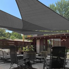 an outdoor patio with chairs, tables and lights on the outside wall is covered in shade from the sun