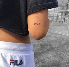 the back of a person's left arm with a small tattoo that reads, 1917