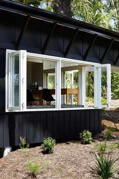 a black house with white trim and windows on the outside, surrounded by grass and trees