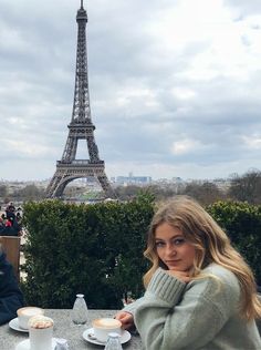 two women sitting at a table in front of the eiffel tower