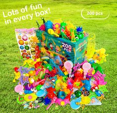 a box filled with lots of toys sitting on top of a lush green field