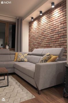 a living room filled with furniture and a brick wall behind the couch is a coffee table