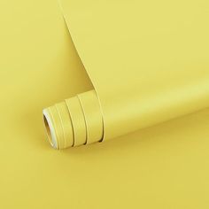 a roll of yellow tape on top of a yellow surface with the end rolled up