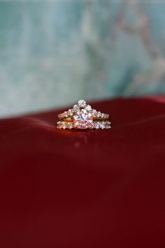 an engagement ring sits on top of a red velvet surface, with two diamonds in the middle