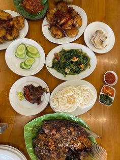 a wooden table topped with lots of plates and bowls filled with different types of food