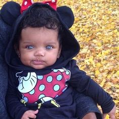 a baby wearing a minnie mouse shirt in a stroller with leaves on the ground