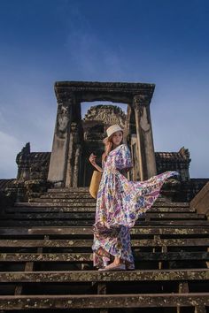 a woman in a long dress standing on some steps