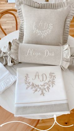 three pillows and two blankets on top of a table with the name alyga dua