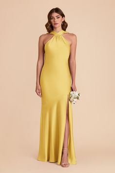 a woman wearing a yellow dress with high slits and a halter neckline