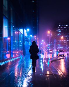 a woman is walking down the street in the rain at night with her coat on