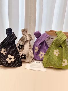 three knitted purses sitting on top of a table next to a bag with flowers