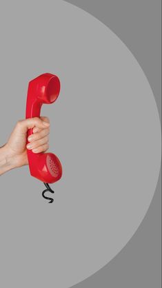 a hand holding an old fashioned red telephone