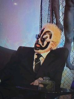 a man wearing a clown mask sitting in front of a tv