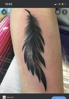 a black and white feather tattoo on the arm