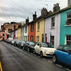 several cars parked on the side of a road in front of colorful buildings and power lines