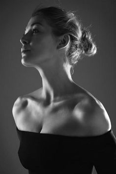 a black and white photo of a woman with her hair up in a high bun