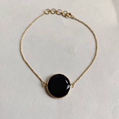 "ITEM DESCRIPTION: >> The bracelet is made from Solid 14K Yellow Gold. Gemstone used is absolutely natural and ethically sourced.  >> Natural Black Onyx in flat cut round shape with bezel setting is studded on it with utmost precision.  >> This is a minimalist design and is absolutely hassle-free and everyday jewelry.  ✓ Gem: Black Onyx ✓ Gem size: 15x15mm ✓ Gem weight: 6.21 carats ✓ Bracelet Length: 7\" Inches + 0.5\" Inch Adjustable ✓ Gold purity: 14K (58.33% approx.) ✓ Gold weight: 1.05 grams  ✓ Gross weight: 2.29 grams The Gold purity is guaranteed and it comes with authentic 14K gold hallmark. Since these Bracelets are handmade, they are Nickel/Lead FREE.  CUSTOMISATION: --> The same design can be made in varying lengths of your choice. --> The same gemstone can be replaced by the one Elegant Black Chain Bracelet For Formal Occasions, Gold Bracelets With Black Enamel, Gold Round Onyx Jewelry, Gold Onyx Round Jewelry, Black Jewelry With Adjustable Chain For Formal Occasions, Black Adjustable Chain Bracelet, Onyx Gemstone Bracelet, Black Round Jewelry With Adjustable Chain, Black Jewelry With Adjustable Round Chain