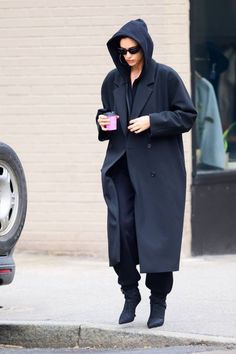 a woman walking down the street while holding a cup