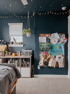 a bedroom with blue walls and lots of clutter on the bed, along with bookshelves