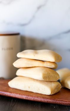 a stack of cookies sitting on top of a wooden cutting board next to a cup