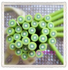 a bunch of green sticks sitting on top of each other in front of a flower