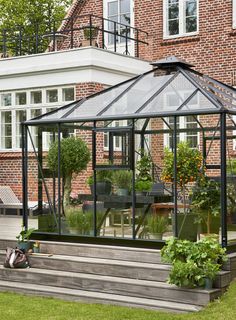 a glass house with steps leading up to it and potted plants on the side