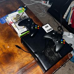 a video game console sitting on top of a wooden table next to a pile of books