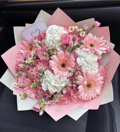 a bouquet of pink and white flowers sitting on top of a car seat