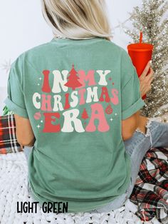 These Comfort Colors In My Christmas Era tees are sure to get you in the holiday spirit! They're comfy, cozy, and OH SO CUTE!  Would make a fabulous gift for anyone on your list, and would be a hit at holiday parties!  Wear it baking cookies and watching Christmas movies or head out shopping, tree picking, or to see Christmas lights!  No matter where the holiday season takes you, you'll love it!  Thanks for stopping by! Shirts are Adult Unisex sizing and they are soft and cozy Rolled Sleeves in pictures are for styling purposes only Props used in photos and NOT included with purchase SIZING These are Unisex Sized T-shirts. UNISEX T-SHIRTS - Women typically wear one size down Models are wearing 1 or 2 sizes up, please order 1 or 2 sizes up if you would like an oversized look Please refer to Simple Christmas Shirts, In My Christmas Era, Christmas Graphic Tee, Christmas Tshirt Ideas, Christmas Shopping Shirts, Ladies Christmas Party, Holiday Treats Gifts, Christmas Chaos, Watching Christmas Movies