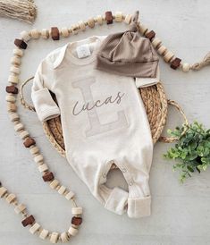 a baby's first birthday outfit is laying on the floor next to a beaded necklace