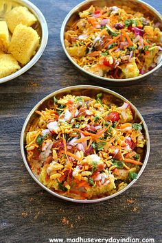 three bowls filled with food sitting on top of a wooden table next to corn chips