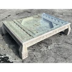 a glass coffee table sitting on top of a cement ground in the middle of nowhere