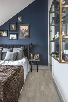 a bedroom with blue walls and pictures on the wall above the bed, along with a wooden floor