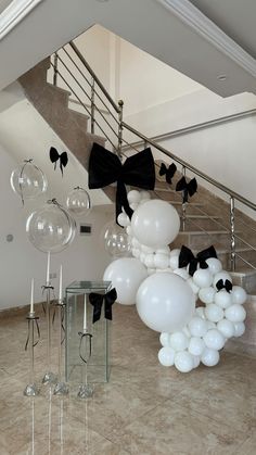 balloons and bows hang from the ceiling in an indoor space with stairs leading up to it