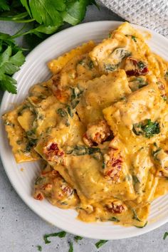 a white plate topped with ravioli covered in cheese and spinach next to parsley