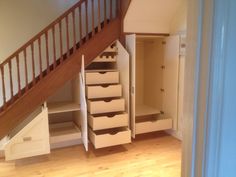 an open closet under the stairs in a room with hard wood floors and white walls