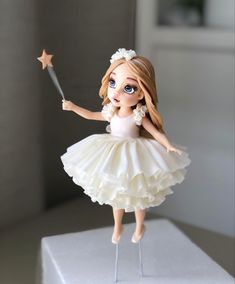 a doll is holding a wand on top of a cake stand with a star in it's hand