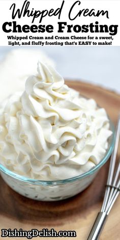 whipped cream is in a glass bowl on a wooden tray with two spoons next to it