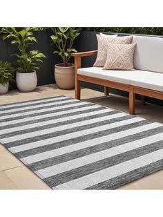 a white and black striped rug sitting on top of a wooden bench next to potted plants