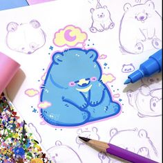 a blue bear sticker sitting on top of a sheet of paper next to some markers