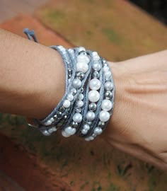 a close up of a person's arm wearing bracelets with pearls on them